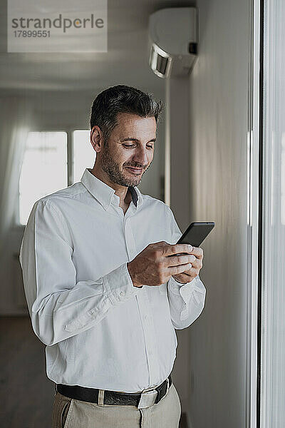 Lächelnder Geschäftsmann benutzt Smartphone im Büro