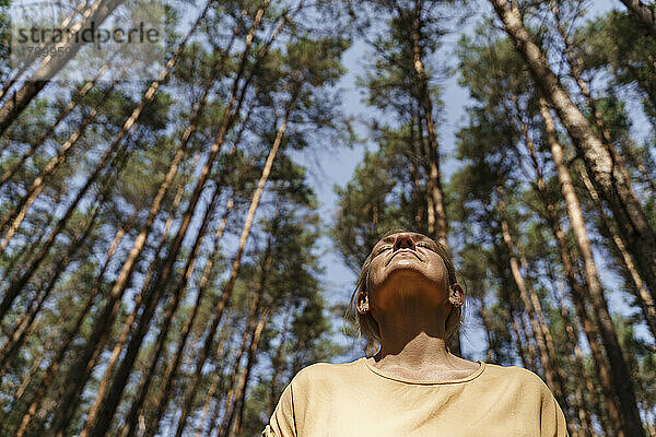 Reife Frau genießt die Natur vor Bäumen im Wald