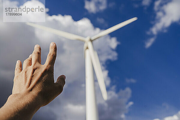 Frau deutet auf eine große Windkraftanlage am Himmel