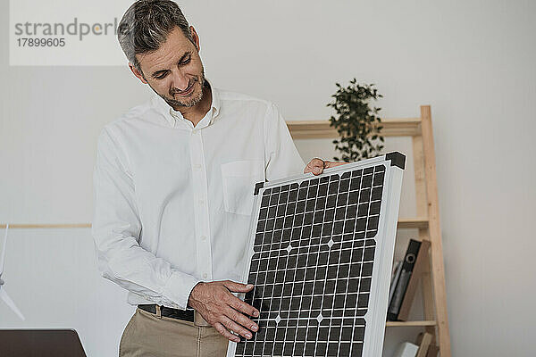 Lächelnder Ingenieur untersucht Solarpanel im Büro