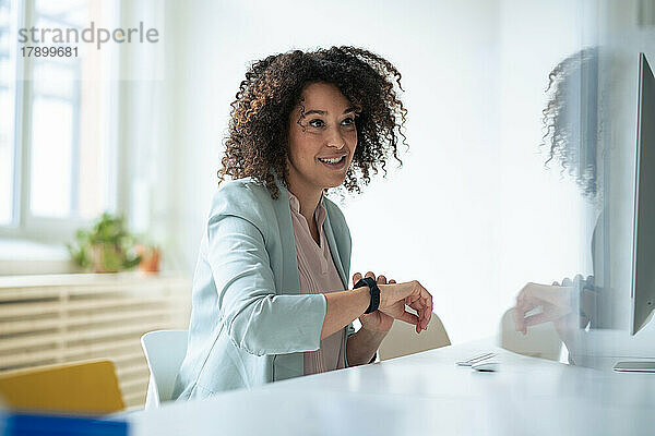 Nachdenkliche Geschäftsfrau trägt Smartwatch im Büro