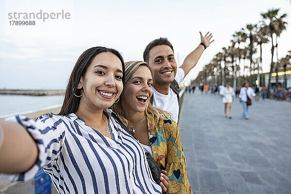 Fröhliche junge Frauen genießen es mit Freunden an der Promenade