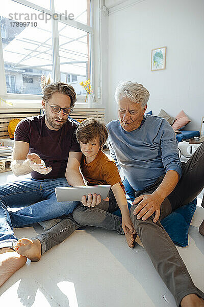 Reifer Mann teilt Tablet-PC mit Sohn und Vater zu Hause