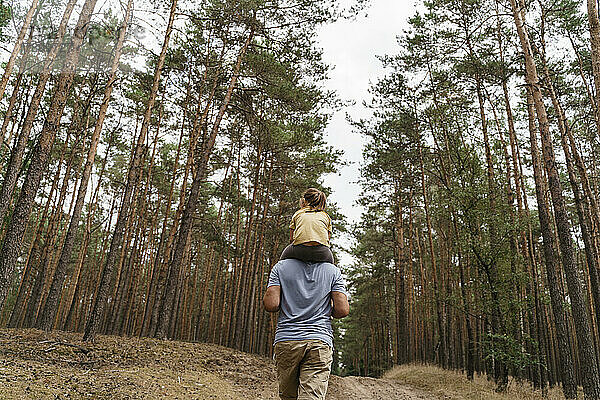 Reifer Mann trägt Mädchen auf Schultern und wandert im Wald