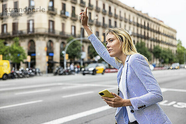 Geschäftsfrau mit erhobener Hand fährt durch die Stadt