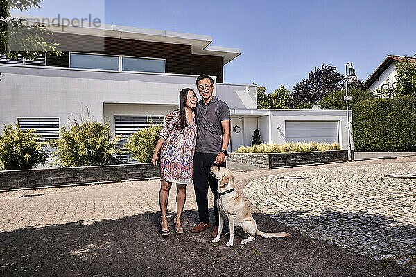 Glückliches älteres Paar mit Hund  der vor dem Haus steht
