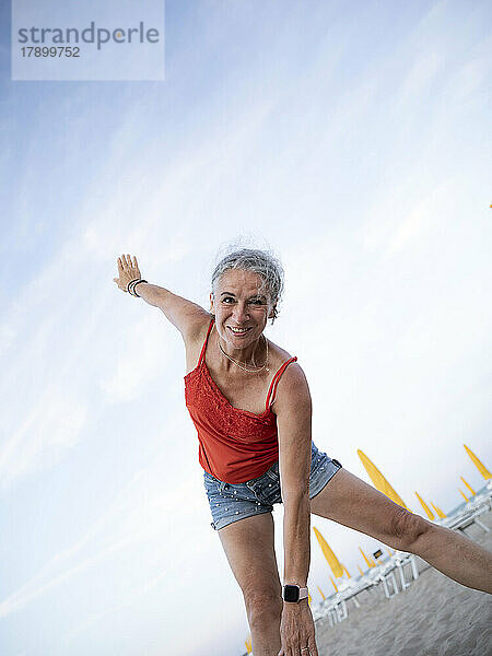 Glückliche ältere Frau macht Sport am Strand