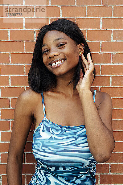 Lächelnde junge Frau vor einer Mauer