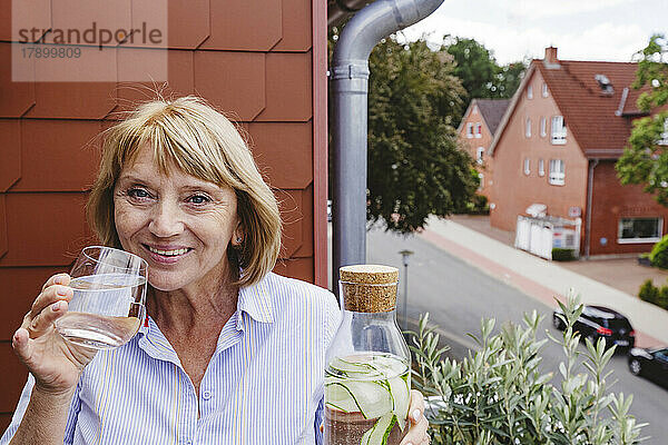 Glückliche ältere Frau mit blonden Haaren  die ein Glas Wasser trinkt