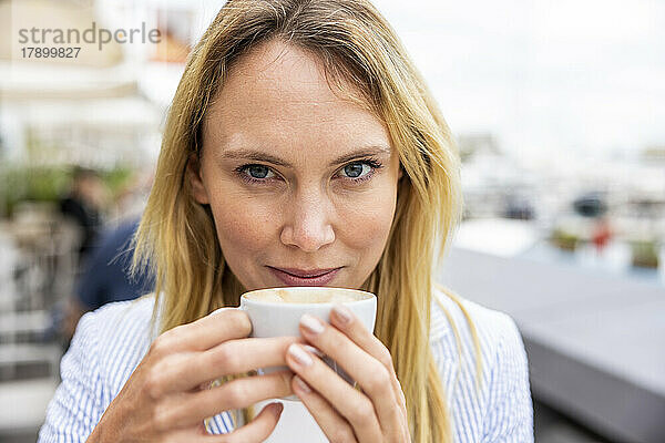 Lächelnde blonde Geschäftsfrau mit Kaffeetasse