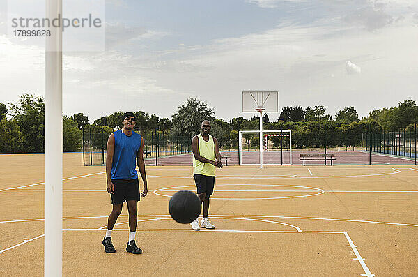 Vater und Sohn schauen sich den herabfallenden Basketball auf dem Sportplatz an