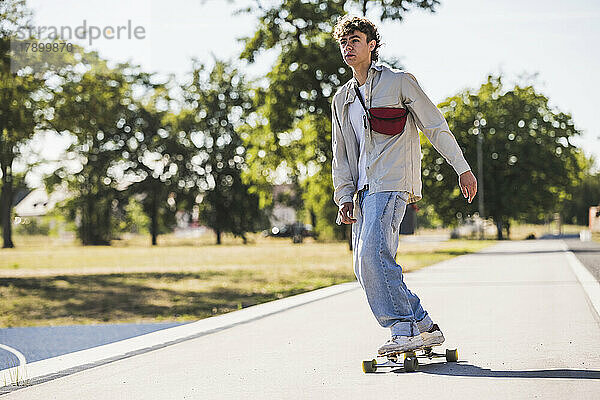 Junger Mann fährt an einem sonnigen Tag Skateboard