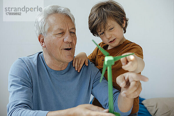 Großvater und Enkel analysieren zu Hause das Modell einer Windkraftanlage