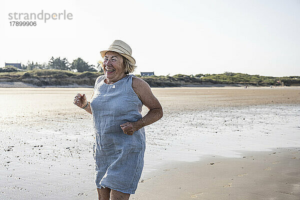 Aktive ältere Frau springt am Strand
