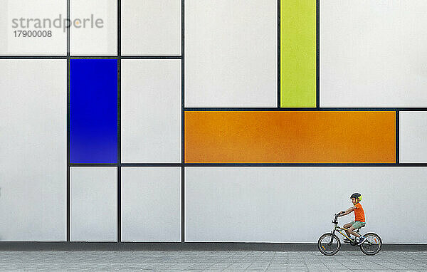Junge fährt BMX-Fahrrad an einer bunt gemusterten Wand