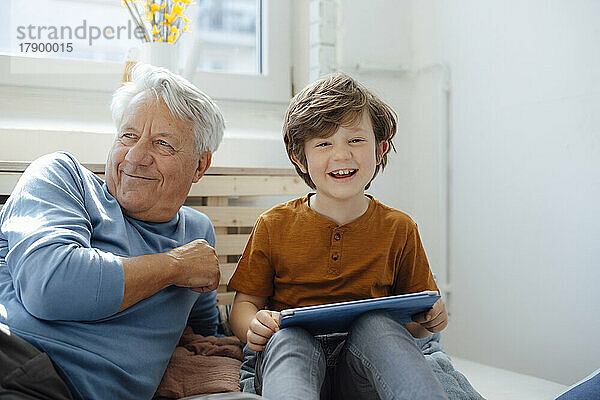 Glücklicher Junge mit Tablet-PC  der zu Hause beim Großvater sitzt