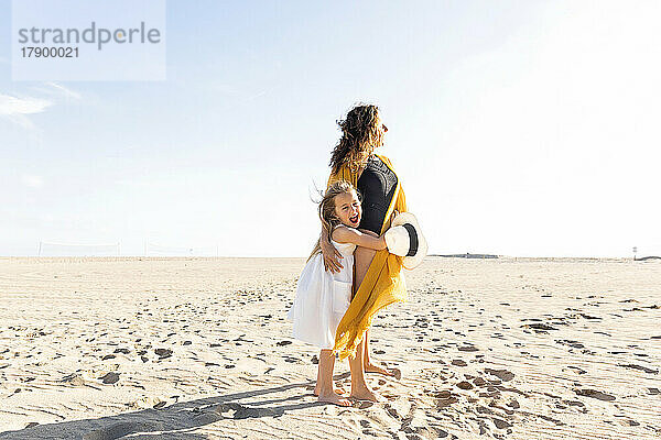 Reife Frau mit Tochter steht an einem sonnigen Tag am Strand