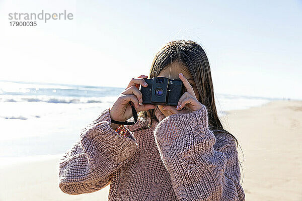 Mädchen mit Kamera fotografiert am Strand