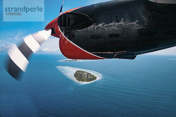 Malediven  Kolhumadulu Atoll  Persönliche Perspektive eines Gleitschirmfliegers über einer kleinen Insel im Indischen Ozean