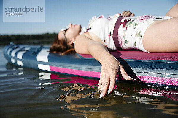 Frau entspannt sich auf SUP-Board im See