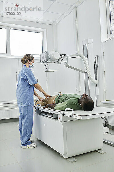 Krankenschwester in Kitteln macht Röntgenaufnahme eines Patienten in der Klinik