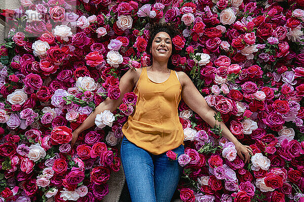 Lächelnde Frau  die auf Rosenblüten liegt