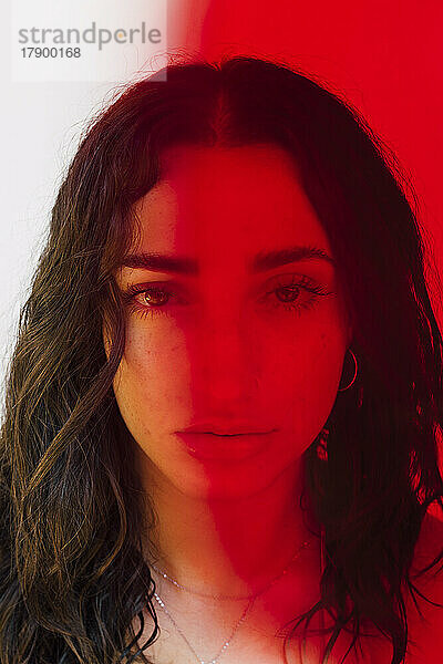 Das Gesicht einer ernsten Frau unter Rotlichteffekt
