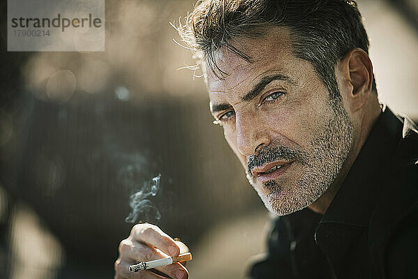 Handsome man with hair stubble smoking cigarette