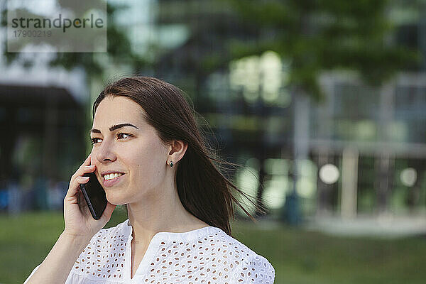 Lächelnde Geschäftsfrau  die ihr Mobiltelefon in die Hand nimmt