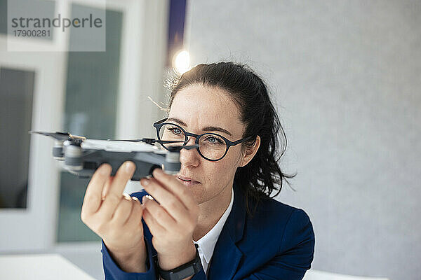 Geschäftsfrau mit Brille blickt auf Drohne