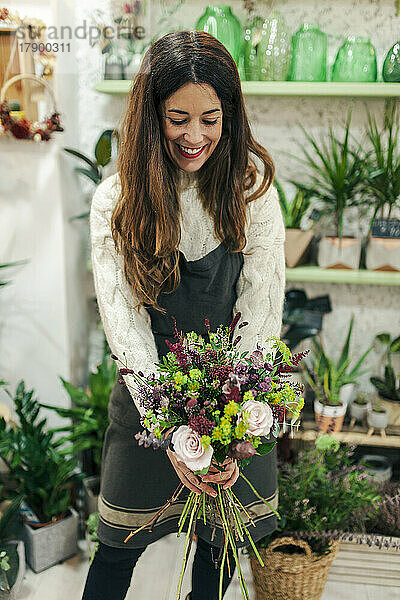 Lächelnder Florist hält Blumenstrauß im Blumengeschäft