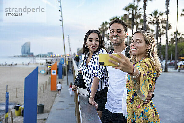 Lächelnde Frau macht Selfie mit Freunden an der Promenade