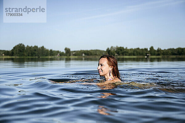 Lächelnde Frau genießt das Schwimmen im See