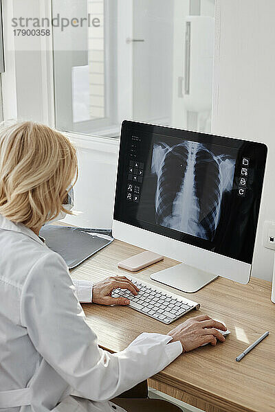 Arzt untersucht Röntgenbild auf Desktop-PC in der Klinik