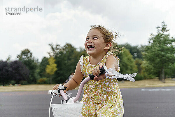 Cheerful girl enjoying cycling at park