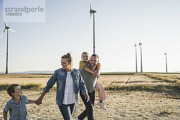 Selbstbewusste Familie geht Händchen haltend durch den Windpark