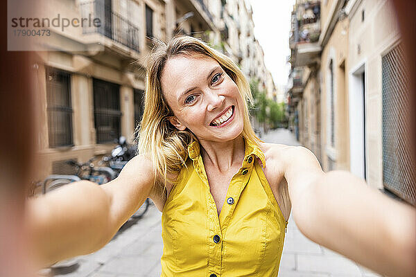 Cheerful woman taking selfie in alley