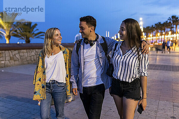 Smiling young man with women walking at promenade