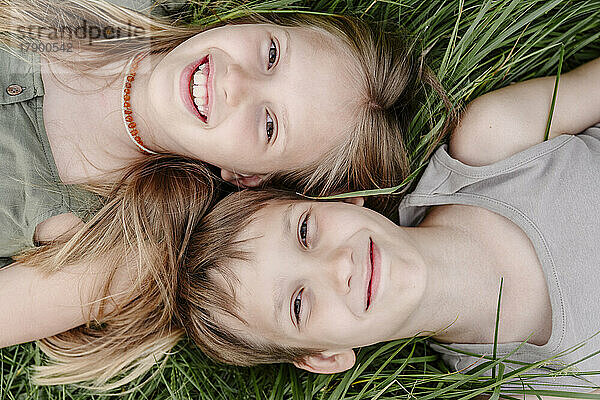 Siblings lying down together on grass