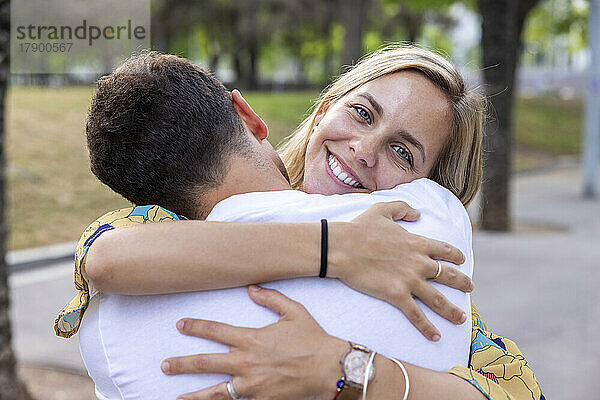 Lächelnde Frau umarmt Freund im Park