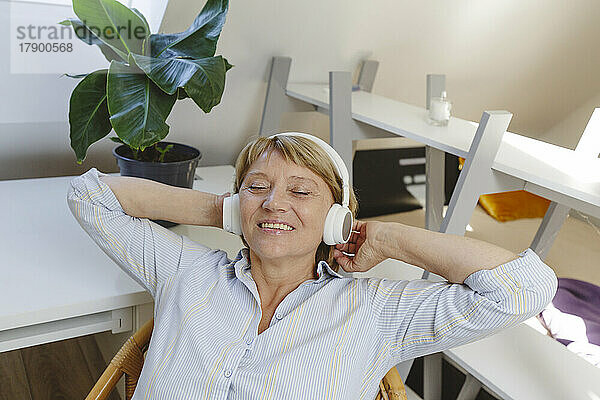 Glückliche ältere Frau  die Musik über drahtlose Kopfhörer hört