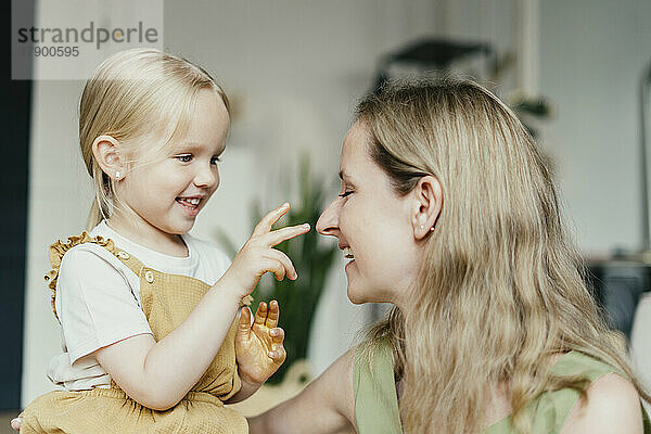 Girl with gold glitter on hands touching mother's nose