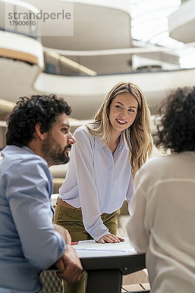 Smiling businesswoman discussing with colleagues in meeting