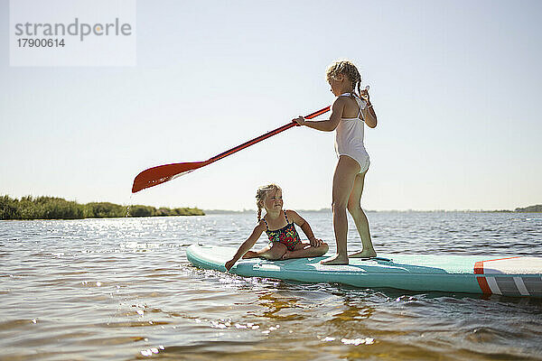 Mädchen haben Spaß auf dem Stand-Up-Paddleboard am See