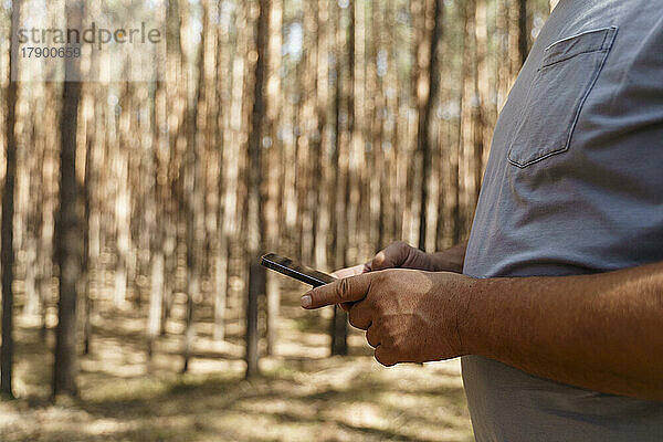 Mann benutzt Smartphone im Wald