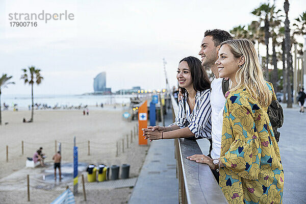 Lächelnde Freunde stehen am Geländer an der Promenade