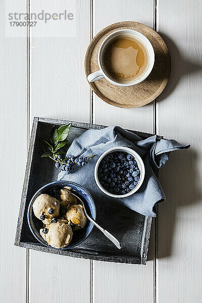 Cup of coffee and bowl of homemade peanut ice cream with blueberries