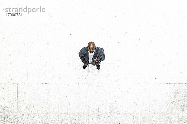 Senior businessman standing on white flooring at railroad station