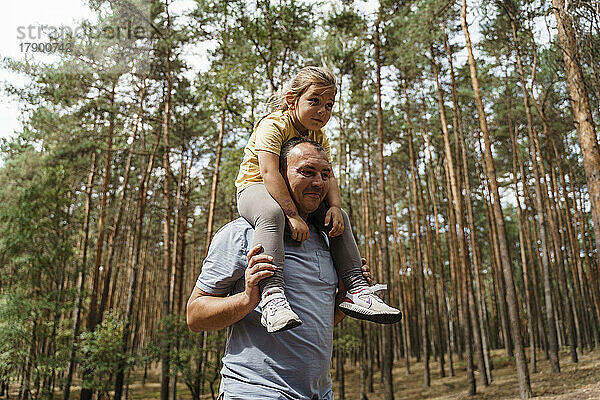 Reifer Mann trägt Mädchen auf Schultern im Wald
