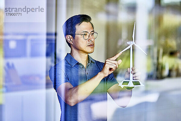 Mann untersucht Windturbinenmodell durch Glas gesehen